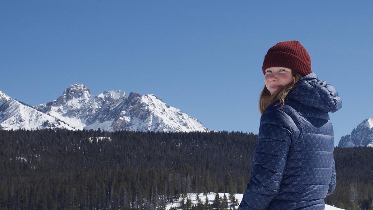 Photo of woman on ski hill with mountain in background.